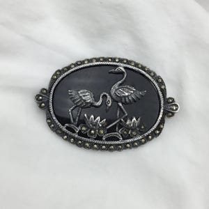 Vintage Sterling silver Marcasite and black onyx gemstone flamingo birds lily pond scene oval brooch. Size 4.8cm x 3.3cm. Weight 13.6g. Good