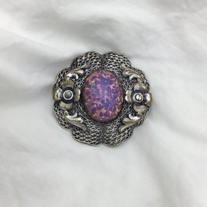 Art Deco-brosch i silverfärgat glas med opalinfärgade drakar och blommig filigranmotiv, 1930- till 1940-tal. Storlek 3,5 cm. Gott skick. Detaljerad.