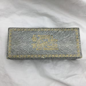 Scatola portagioie rettangolare vintage C1930 con dettagli in oro grigio e velluto nero all'interno. Per gemelli o orecchini o può essere usata come spilla. Misura 9,2 cm.