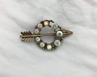 Spilla piccola vintage Aurora Borealis (leggermente arcobaleno) con cerchio di strass e freccia color oro. Annata dagli anni '50 agli anni '60. Dimensioni 4 cm x 2,2 cm di larghezza