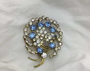 Vintage 1950s mid blue & white rhinestone glass and brass flower spray round large brooch. Size 6cm x 4.5cm widest. Good condition. Lovely