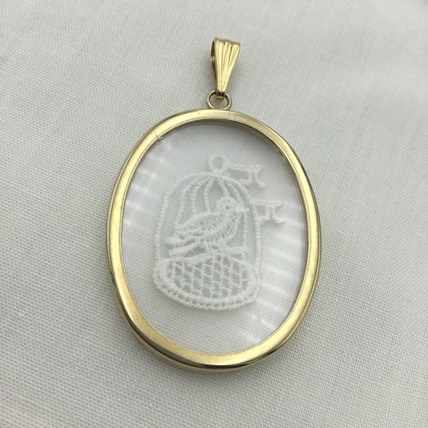 Oiseau en dentelle blanche dans une cage en verre et pendentif doré. Ovale de grande taille 4,6 cm x 3,5 cm. Insolite.