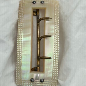 May include: A vintage mother of pearl belt buckle with a brass buckle and four prongs. The buckle has a checkered pattern and is in good condition.