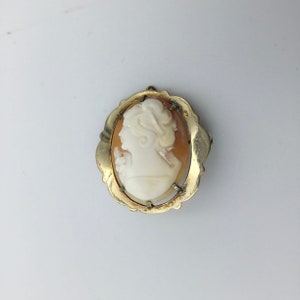 Broche vintage con camafeo de oro laminado y concha. 3,1 cm x 2,4 cm. Años 50. El camafeo está en buen estado, con un ligero desgaste en el marco donde se ve el latón. Precio económico.
