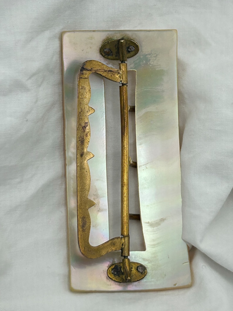 Puede incluir: Una hebilla de cintur&oacute;n vintage de n&aacute;car con un cierre de lat&oacute;n. La hebilla es rectangular y tiene un dise&ntilde;o decorativo en la parte delantera. El cierre es con bisagras y tiene un peque&ntilde;o pomo redondo en la parte superior.