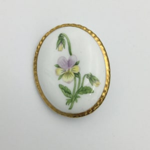 Vintage ceramic pansy brooch, violet and yellow and green leaves picture brooch with gold tone edges and back. Size 5.2cm x 4.2cm widest