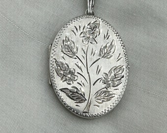 Vintage Sterling silver flowers oval locket fancy engraved front medium size 4.2cm & 11mm rings x 3.2cm. 1976 England hallmark. Weight 9.8g.