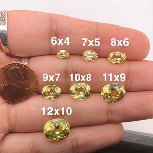 May include: A set of yellow oval gemstones of different sizes, labelled with their dimensions in millimetres. The gemstones are arranged in a row on a hand, with the smallest gemstone at the top and the largest gemstone at the bottom. The gemstones are all cut in a similar style, with a smooth, polished surface.