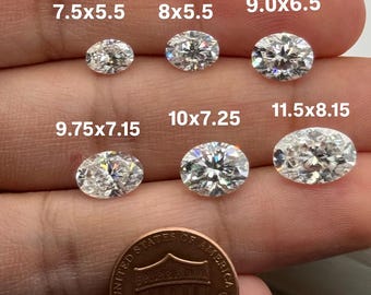 May include: Six oval-cut gemstones of varying sizes are displayed, with measurements in millimeters. The gemstones are clear and faceted, reflecting light. A U.S. one-cent coin is included for size comparison.