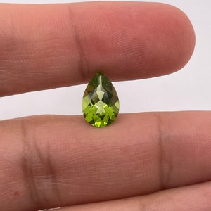 May include: A pear-shaped green peridot gemstone with a faceted cut.