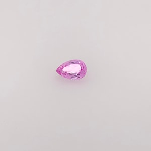 May include: A pear-shaped pink gemstone with facets.