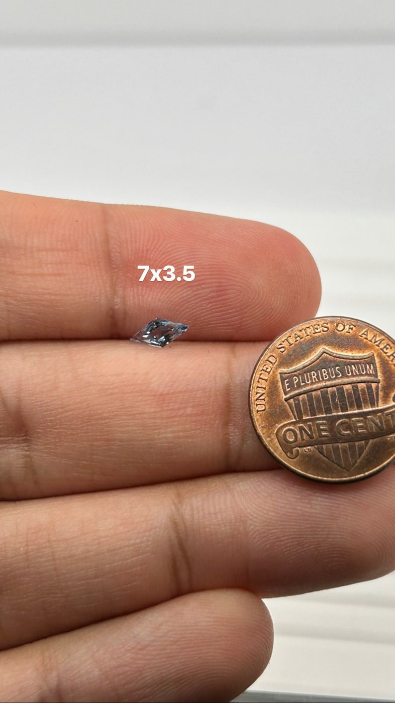 Peut inclure: Une pierre pr&eacute;cieuse transparente et facet&eacute;e mesurant 7 mm x 3,5 mm, tenue dans une main &agrave; c&ocirc;t&eacute; d'une pi&egrave;ce de un centime d'euro pour comparaison de taille.