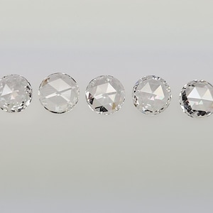 May include: Five round, clear, faceted gemstones on a white background.