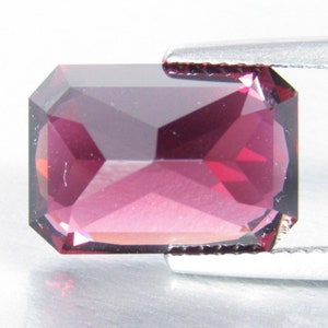 Peut inclure: Une pierre pr&eacute;cieuse rectangulaire rose fonc&eacute; avec une taille facet&eacute;e. La pierre pr&eacute;cieuse est maintenue en place par une pince.