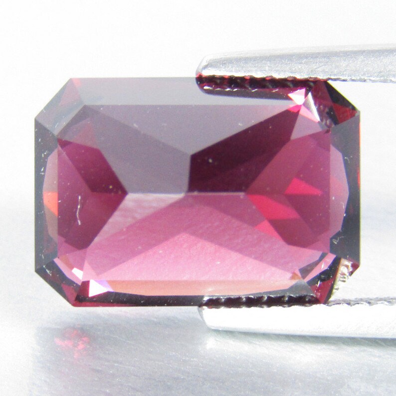 Peut inclure: Une pierre pr&eacute;cieuse rectangulaire rose fonc&eacute; avec une taille facet&eacute;e. La pierre pr&eacute;cieuse est maintenue en place par une pince.