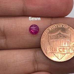 May include: A 5mm pink star ruby gemstone, next to a US penny for size comparison.