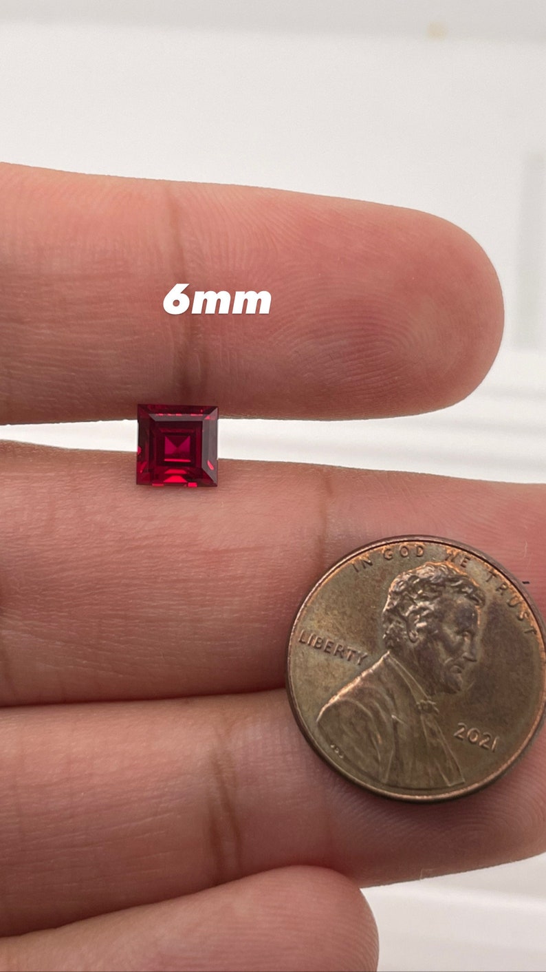 May include: A 6mm square-shaped ruby gemstone, shown next to a US penny for size comparison.