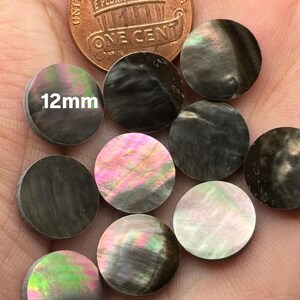 May include: Nine iridescent black mother of pearl shell cabochons, each measuring 12mm in diameter. The cabochons have a variety of colors, including green, pink, and white.