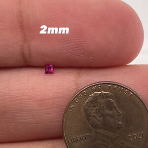May include: A 2mm square-shaped pink gemstone, shown next to a US penny for size comparison.