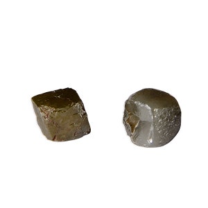 May include: Two rough, grey-brown, cubic crystals. The crystals are similar in size and shape, but one is slightly darker than the other.
