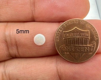 May include: A white opal gemstone measuring 5mm in diameter, shown next to a US penny for size comparison.