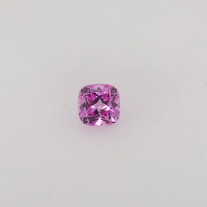 May include: A cushion-cut pink gemstone with facets.
