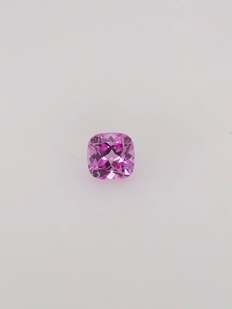 May include: A cushion-cut pink gemstone with facets.