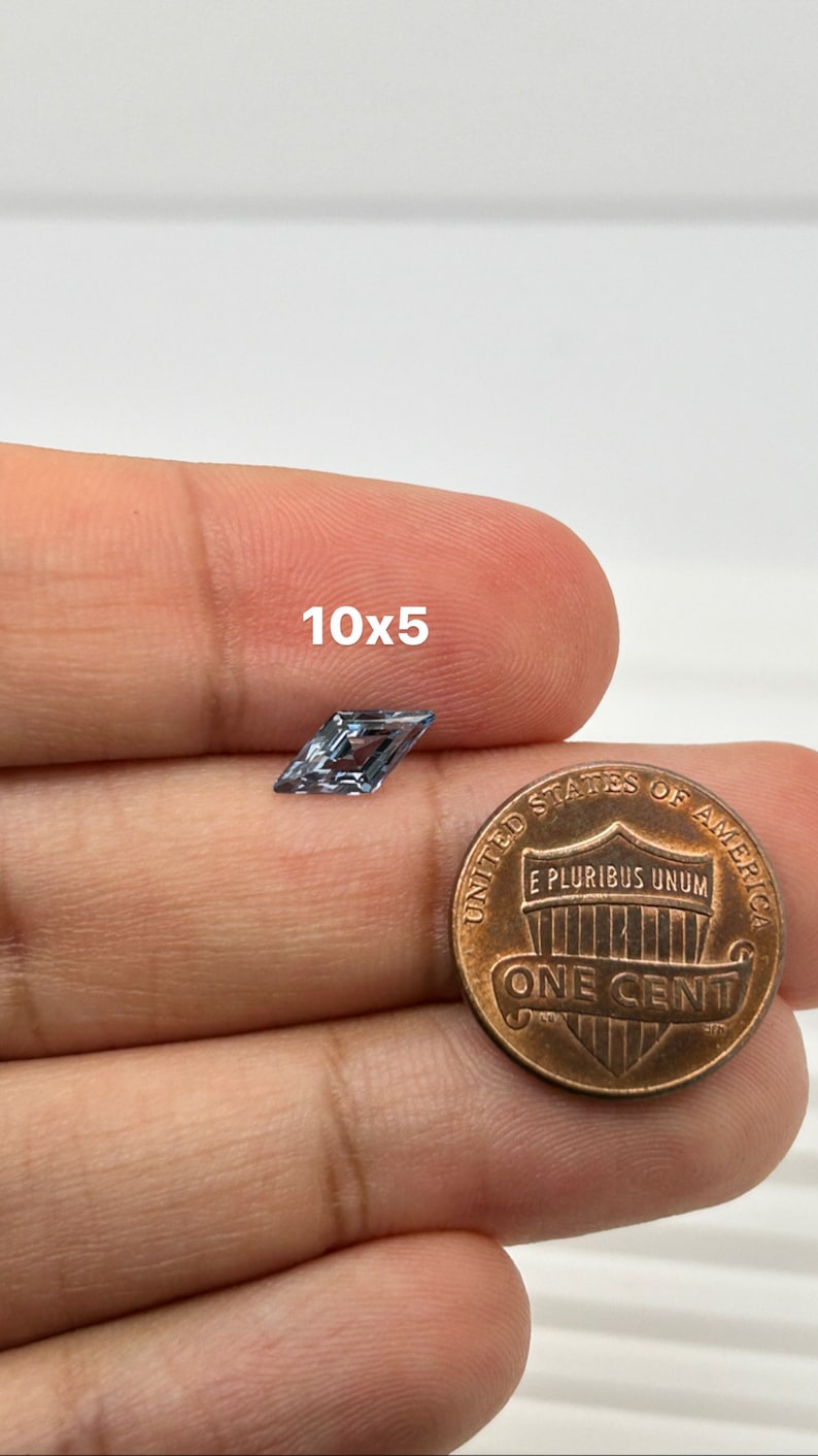 Peut inclure: Une pierre pr&eacute;cieuse bleu clair de forme carr&eacute;e, mesurant 10x5 millim&egrave;tres, est pr&eacute;sent&eacute;e &agrave; c&ocirc;t&eacute; d'un penny am&eacute;ricain pour comparaison de taille.