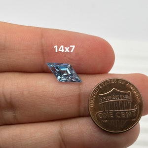 Peut inclure: Une pierre pr&eacute;cieuse bleu clair de forme carr&eacute;e, mesurant 14x7 mm, est pr&eacute;sent&eacute;e &agrave; c&ocirc;t&eacute; d'un centime d'euro pour comparaison de taille.