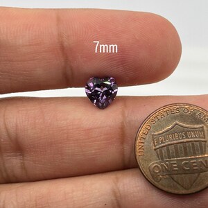K&ouml;nnte beinhalten: Ein 7 mm gro&szlig;er herzf&ouml;rmiger violetter Edelstein, neben einem US-Penny zum Gr&ouml;&szlig;envergleich.