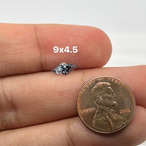 Peut inclure: Une pierre pr&eacute;cieuse bleu clair de forme rectangulaire, mesurant 9x4,5 mm, est pr&eacute;sent&eacute;e &agrave; c&ocirc;t&eacute; d'une pi&egrave;ce de monnaie d'un centime am&eacute;ricain pour comparaison de taille.