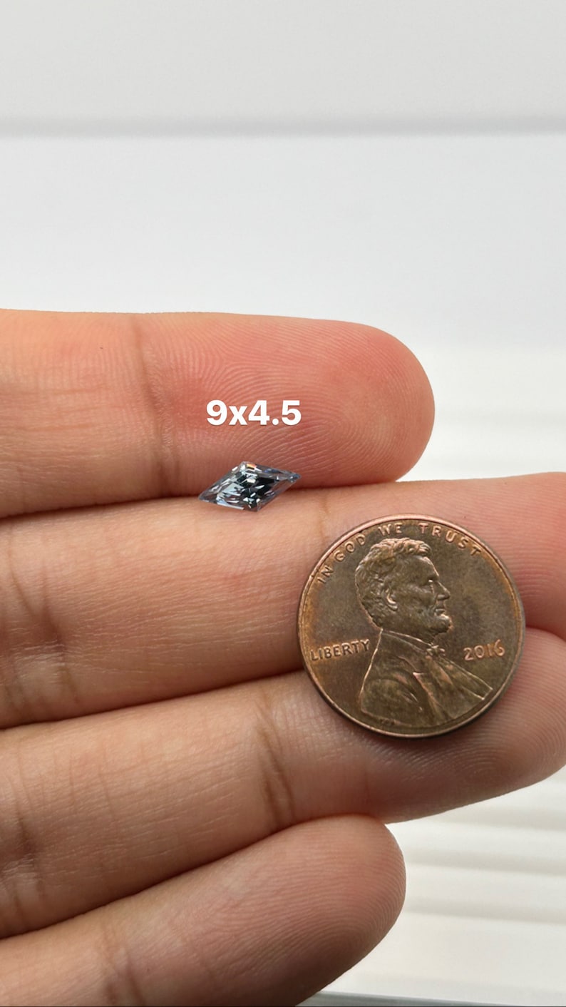 Peut inclure: Une pierre pr&eacute;cieuse bleu clair de forme rectangulaire, mesurant 9x4,5 mm, est pr&eacute;sent&eacute;e &agrave; c&ocirc;t&eacute; d'une pi&egrave;ce de monnaie d'un centime am&eacute;ricain pour comparaison de taille.