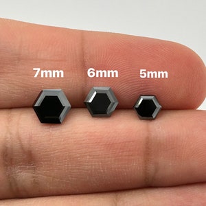 May include: Three black hexagonal diamonds, 7mm, 6mm, and 5mm in size, are displayed on a finger.