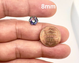 May include: A 8mm iridescent gemstone with a hexagonal shape, displayed next to a US penny for size comparison.