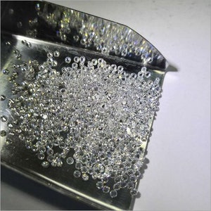 Puede incluir: Una vista cercana de una pala de metal llena de diamantes redondos, transparentes y sueltos. Los diamantes son peque&ntilde;os y parecen ser de tama&ntilde;o uniforme.