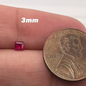 May include: A 3mm square-shaped ruby gemstone, shown next to a US penny for size comparison.