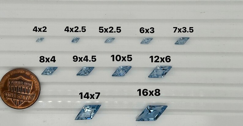 Peut inclure: Comparaison de diff&eacute;rentes tailles de pierres pr&eacute;cieuses facett&eacute;es bleu clair, allant de 4x2 pouces &agrave; 16x8 pouces. Un centime am&eacute;ricain est inclus pour l'&eacute;chelle.