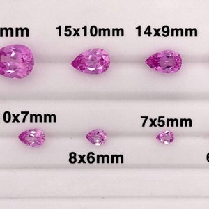 May include: A collection of pink pear-shaped gemstones of various sizes, ranging from 5x3mm to 18x13mm. The gemstones are arranged in rows on a white surface, with a penny for scale.