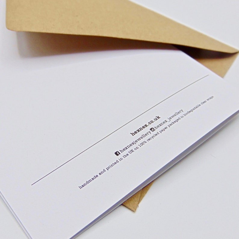 May include: A white card with black text that reads "hexnex.co.uk", "hexnexjewellery", "hexnex jewellery", "handmade and printed in the UK on 100% recycled paper packaged in biodegradable clear wrap".