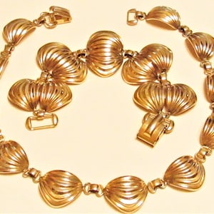 May include: A gold-tone necklace with a scalloped design. The necklace is made of metal and has a clasp closure.