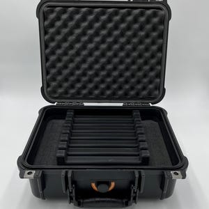 May include: Black hard-shell case with a foam interior and a handle. The case is open and has multiple slots for holding items.