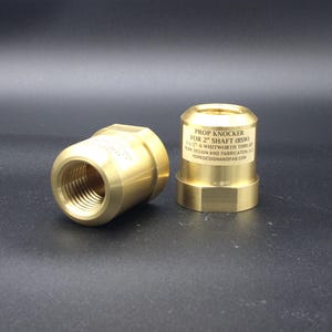 May include: Two gold-colored metal prop knockers for a 2-inch shaft. The knockers are designed for a 6 Whitworth thread. The text "PROP KNOCKER FOR 2" SHAFT (6SW) 6" WHITWORTH THREAD JOHN DESMAN AND FABRICATION LTD. JOHNDESMANFAB.COM" is engraved on the side of one knocker.