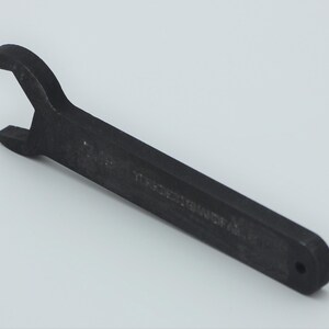 May include: A black wrench with a long handle and a single open end. The wrench has the text "17/16" and "MADE IN USA" printed on the handle.