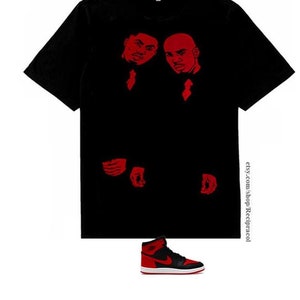 May include: Black t-shirt with a red graphic print of two men in suits. Red and black sneakers with a white swoosh.