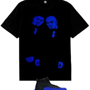 May include: A black short-sleeve t-shirt featuring a blue graphic print of two individuals in suits on the chest, paired with a black and blue high-top sneaker with a textured side panel and a solid blue sole, shown below the t-shirt.