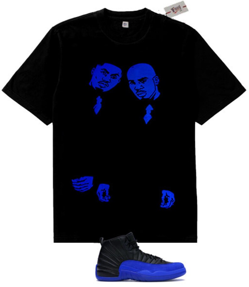 May include: A black short-sleeve t-shirt featuring a blue graphic print of two individuals in suits on the chest, paired with a black and blue high-top sneaker with a textured side panel and a solid blue sole, shown below the t-shirt.