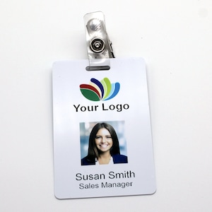 May include: White employee ID badge with a clear plastic clip. The badge features a company logo, the text "Your Logo", a photo of a woman, and the text "Susan Smith, Sales Manager."