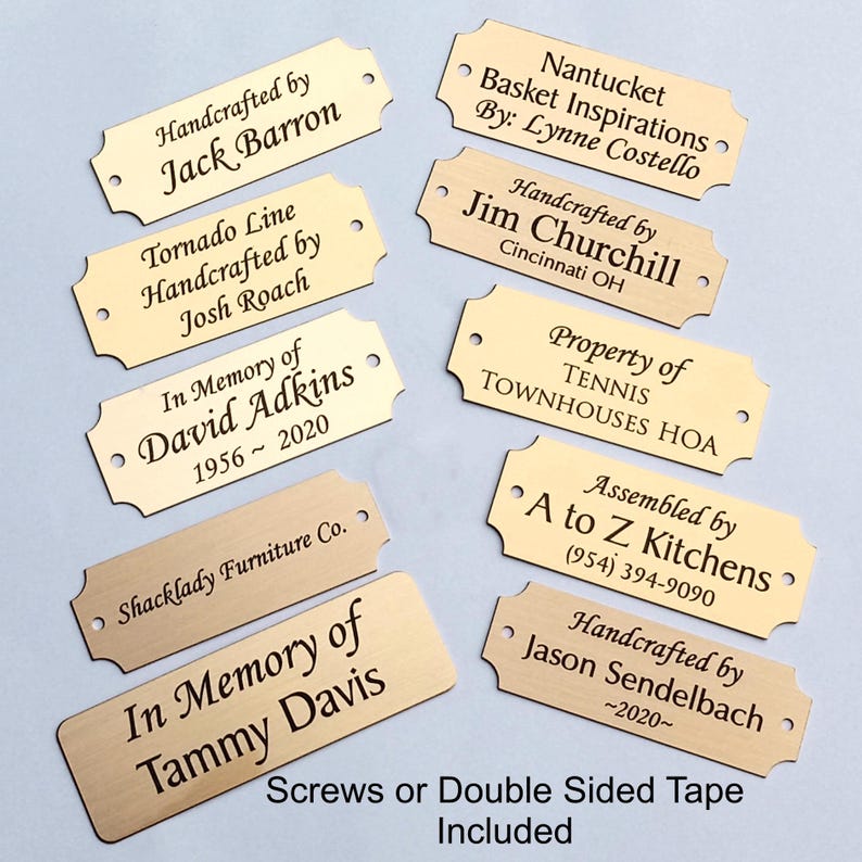 Puede incluir: Una colecci&oacute;n de placas de identificaci&oacute;n de metal dorado con texto negro grabado. Las placas tienen una forma decorativa e incluyen texto como "Handcrafted by Jack Barron" e "In Memory of David Adkins 1956-2020".