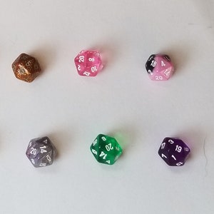 May include: Six 20-sided dice in various colors, including gold, pink, black and white, green, and purple. The dice are all numbered 1 through 20.