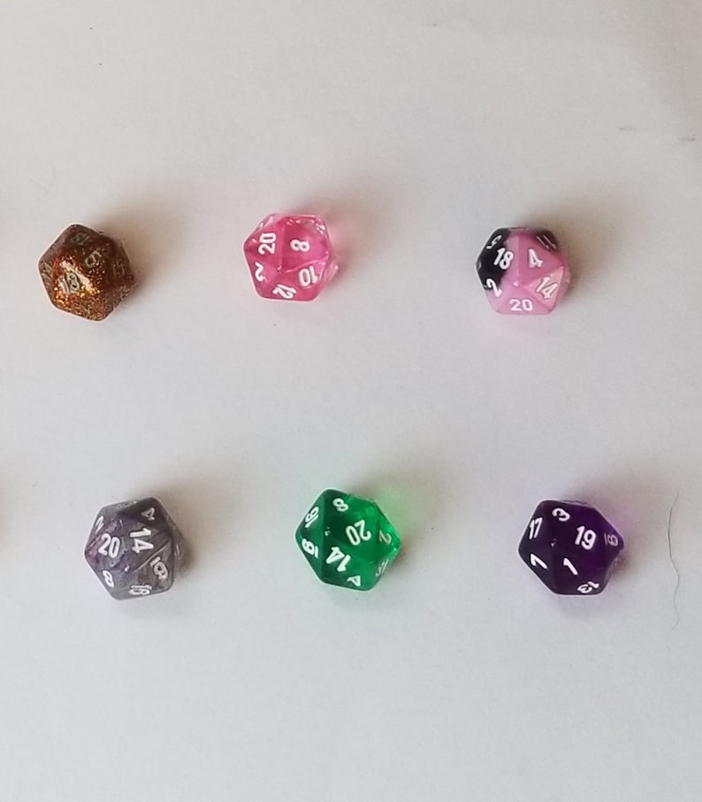 May include: Six 20-sided dice in various colors, including gold, pink, black and white, green, and purple. The dice are all numbered 1 through 20.